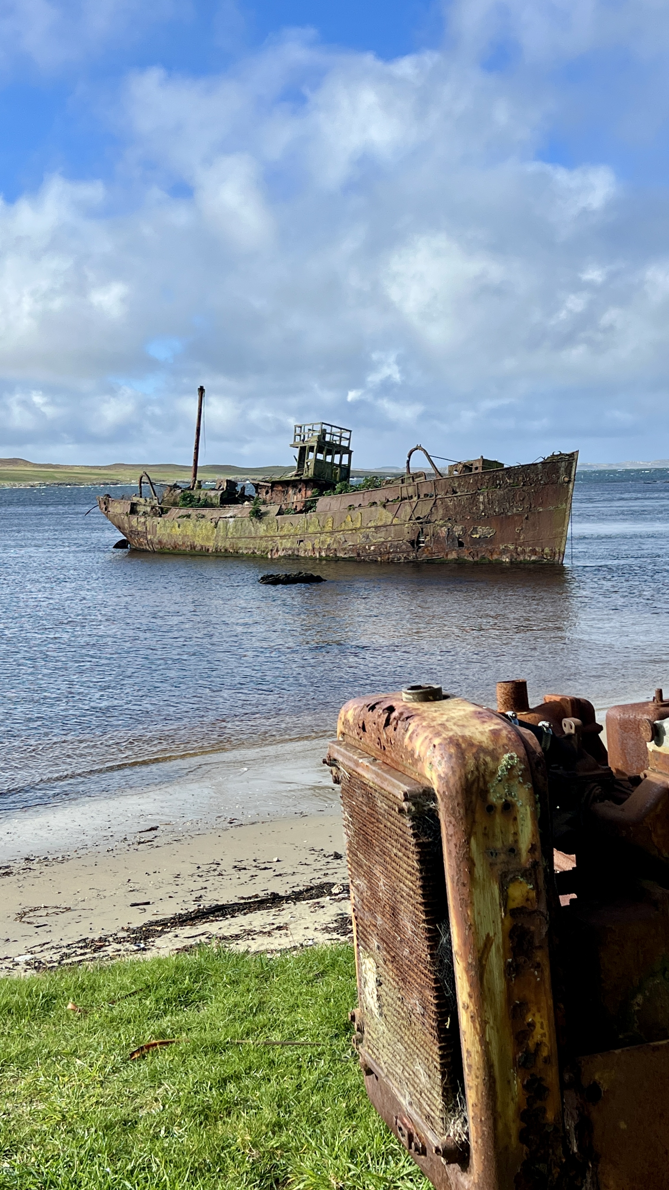 rusted boat tilting in harbour